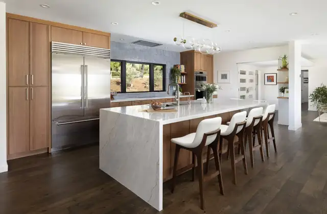 San Roque Santa Barbara kitchen with long marble waterfall island, white counter stools and stainless built-in refrigerator