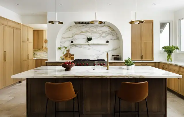 Modern Mediterranean kitchen in Santa Barbara with arched marble range alcove, light oak cabinets, white stone island and leather counter stools