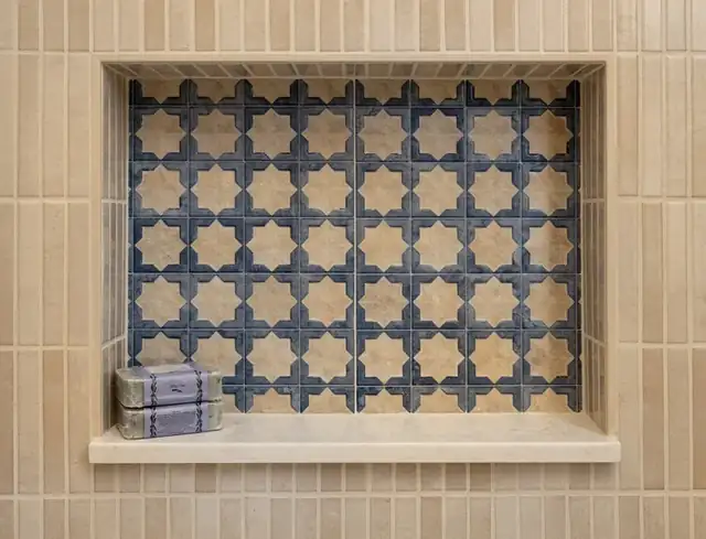 Recessed shower niche with blue and cream patterned tile framed by tan stacked tile in a Santa Barbara bathroom
