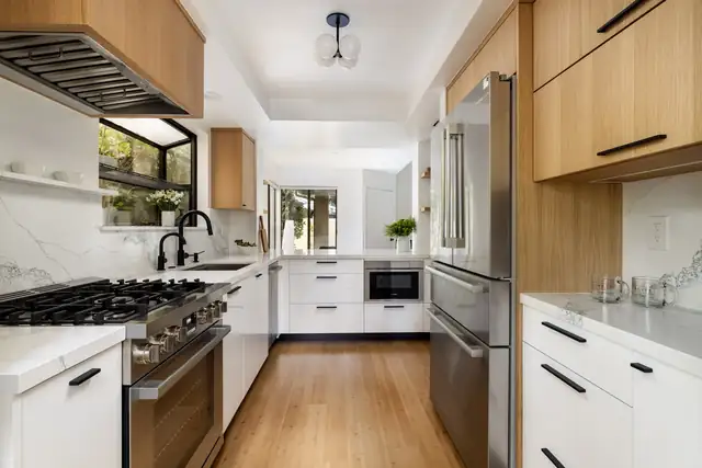 Santa Barbara galley kitchen with white oak upper cabinets, white lower cabinets, gas range and window over the sink