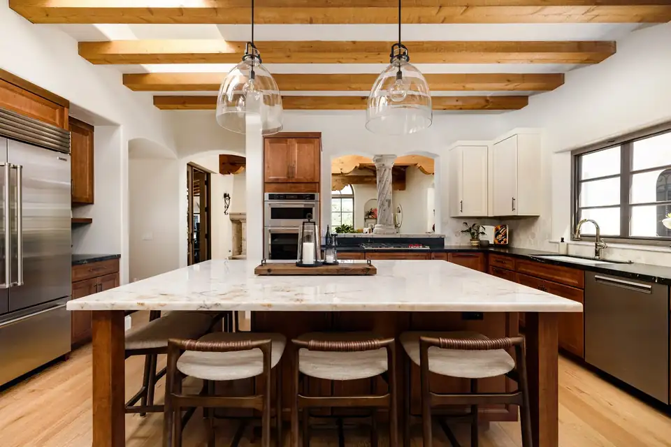 Kitchen remodeling Santa Barbara: Italian Villa style kitchen with maple cabinets in a warm Amaretto finish, quartzite island with seating, wood ceiling beams and glass pendants