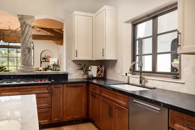 Charcoal quartzite perimeter counters, maple base cabinets and arched window in an Italian Villa style Santa Barbara kitchen