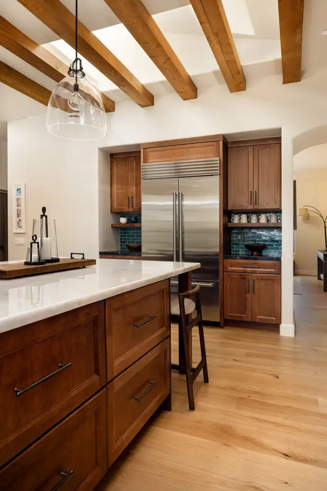 Glass-front maple cabinet with green tile backsplash and dark stone counter in a Santa Barbara kitchen remodel